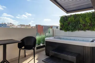 a hot tub on a balcony with a table and a chair at Hilton Garden Inn Athens Syggrou Avenue in Athens