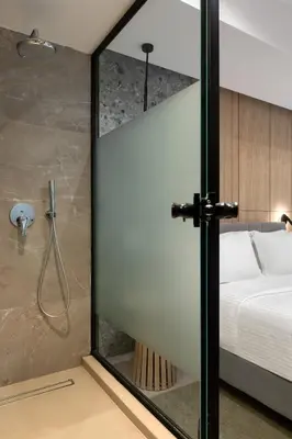 a glass shower door in a bedroom with a bed at Hilton Garden Inn Athens Syggrou Avenue in Athens