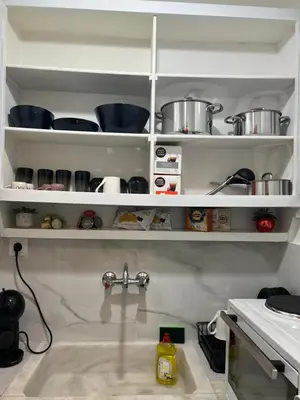 a kitchen with white shelves with pots and pans at Apartment in Athens in Athens