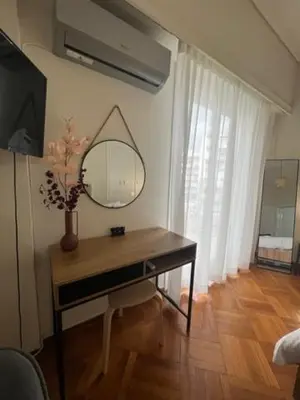 a room with a table with a mirror and a vase with flowers at Apartment in Athens in Athens