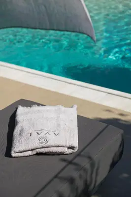 a towel sitting on a table next to a pool at AVAL Riviera in Lagonissi