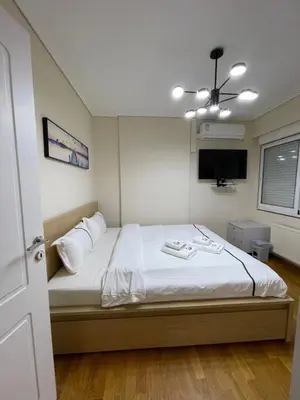 a bedroom with a bed with white sheets and a ceiling fan at Ammo Glyfada Residences in Athens