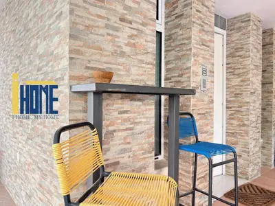 two chairs and a table on a porch with a fireplace at Ammo Glyfada Residences in Athens