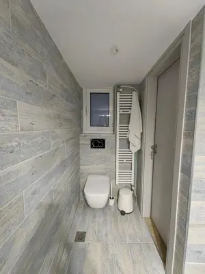 a bathroom with a toilet and a tv on a wall at Hermes - Acropolis Residence Apartment in Athens