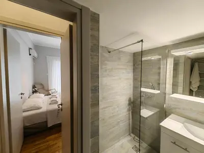 a bathroom with a shower and a sink and a mirror at Hermes - Acropolis Residence Apartment in Athens