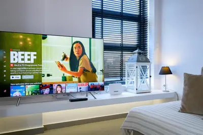a large screen tv in a bedroom with a bed at Stylish 2BR flat with stunning views & prv parking in Athens