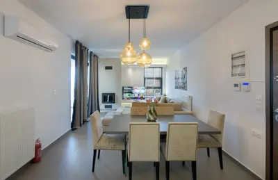 a dining room and living room with a table and chairs at Stylish 2BR flat with stunning views & prv parking in Athens