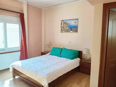 a bedroom with a bed with blue pillows and a window at Bright 3bed 3bath 10 min walk Acropolis in Athens