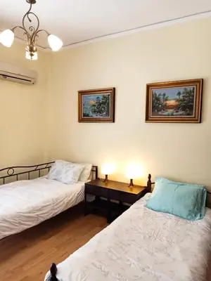 a room with two beds and a table with two lamps at Bright 3bed 3bath 10 min walk Acropolis in Athens