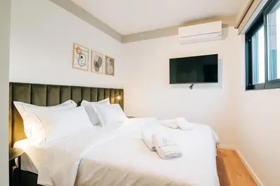 a bedroom with a white bed with a tv on the wall at Athesense Suites in Athens