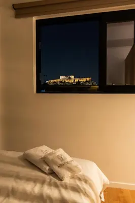 a bedroom with a window with a pillow on a bed at Athesense Suites in Athens