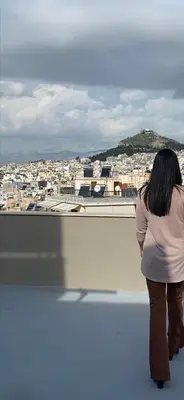 a woman standing on top of a building looking at a city at The Athenian Oasis in Athens
