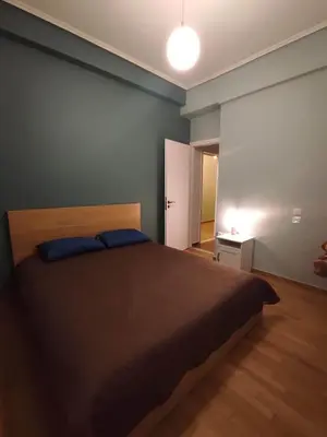 a bedroom with a bed and a blue wall at Comfy in Kypseli in Athens