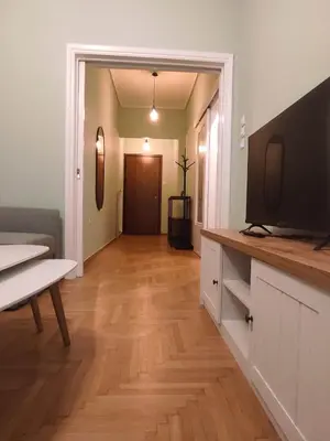a living room with a television and a wooden floor at Comfy in Kypseli in Athens