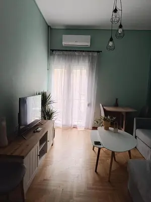 a living room with a television and a table at Comfy in Kypseli in Athens