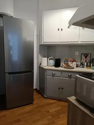a kitchen with a stainless steel refrigerator and white cabinets at Comfy in Kypseli in Athens