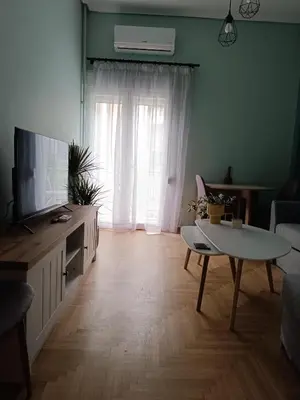 a living room with a television and a table at Comfy in Kypseli in Athens