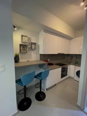 a kitchen with white cabinets and blue chairs at Monastiraki Heart - Luxury Apartment Athens in Athens