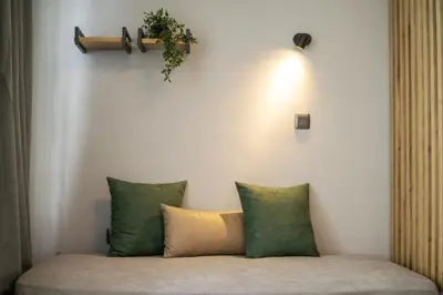 a couch with four pillows and a plant on the wall at Karma Athens II in Athens
