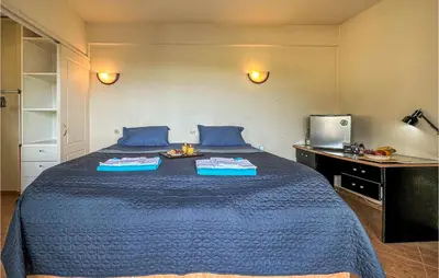 a large bed in a room with a blue bedspread at 3 Bedroom Cozy Home In Koropi in Koropíon
