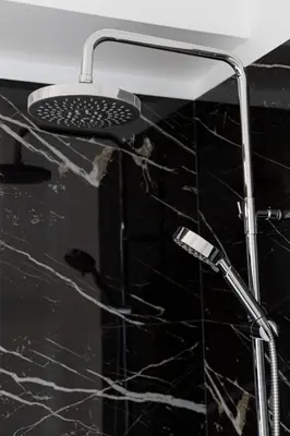 a shower head in a bathroom with black marble at Hip And Fun Apt B in Athens