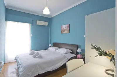 a bedroom with blue walls and a bed with two chairs at Andromaxi 2BR Apt near SNFCC, AC, WiFi in Athens
