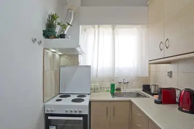 a white kitchen with a stove and a sink at Andromaxi 2BR Apt near SNFCC, AC, WiFi in Athens