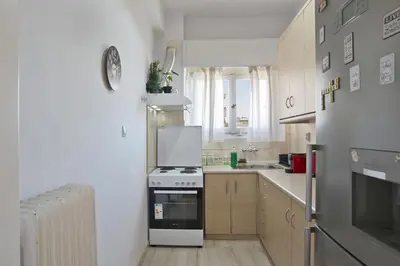 a white kitchen with a stove and a sink at Andromaxi 2BR Apt near SNFCC, AC, WiFi in Athens