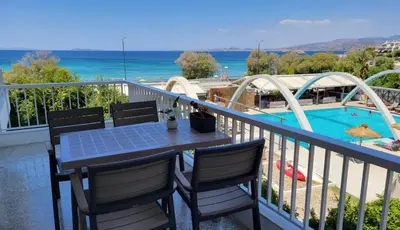 a table and chairs on a balcony with a pool at VISTA MARE beachfront apartment. in Saronida