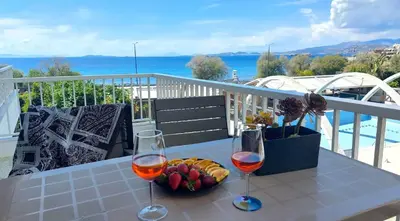 a table with two glasses of wine and a bowl of fruit at VISTA MARE beachfront apartment. in Saronida