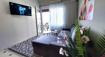 a living room with a couch and a tv on a wall at VISTA MARE beachfront apartment. in Saronida