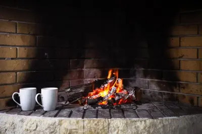 two white coffee cups sitting next to a brick fireplace at Divine Home Beach Retreat in Anavissos