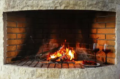 a fire in a brick oven with two glasses of wine at Divine Home Beach Retreat in Anavissos