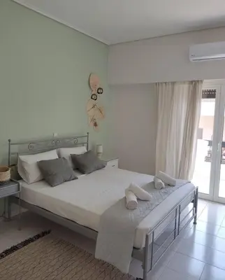 a white bedroom with a large bed and a window at M.V Apartment in Athens