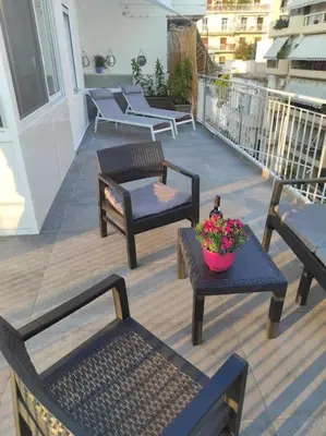 a balcony with chairs and a table with a bowl of flowers at Athens Acropolis View in Athens