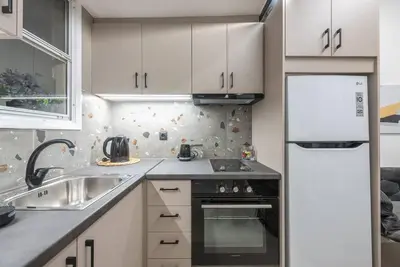 a kitchen with white cabinets and a sink and a refrigerator at Ano Patisia Station Studio in Athens