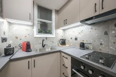 a kitchen with white cabinets and a sink and a stove at Ano Patisia Station Studio in Athens