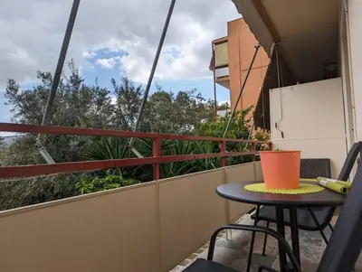 a table and chairs on a balcony with a view at Cozy apartm.near Metro Ag.Marina in Athens