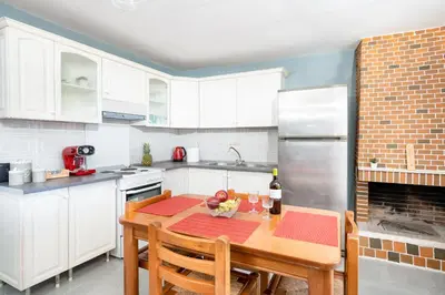 a kitchen with white cabinets and a table with a bottle of wine at Zen Hilltop by A&D Properties in Porto Rafti