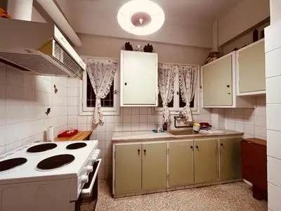a kitchen with white cabinets and a sink and a stove at Grandma's Apartment in Athens