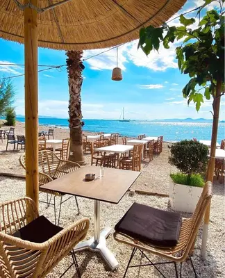 a beach with tables and chairs and the ocean at Seaside Apartment by Flisvos Marina in Athens