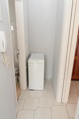 a white bathroom with a toilet and a white tile floor at Bluehouse in Porto Rafti