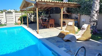 a swimming pool with chairs and a pergola next to a house at Luxury apartment SEA HELM with private swimming pool and BBQ in Lagonissi