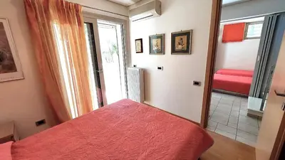a bedroom with a red bed and a bathroom at Luxury apartment SEA HELM with private swimming pool and BBQ in Lagonissi