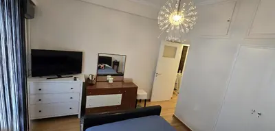 a living room with a tv and a dresser and a chandelier at Syntagma Plaka Getaway Apartment in Athens