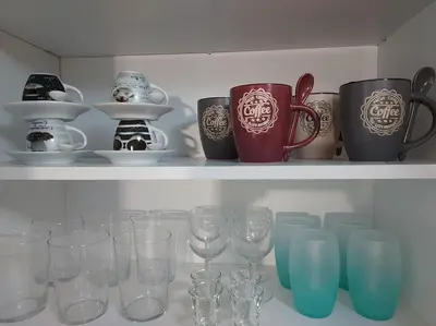 a shelf with wine glasses and cups on it at Anastasia's apartment with yard in Athens