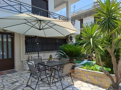 a table and chairs with an umbrella on a patio at Anastasia's apartment with yard in Athens