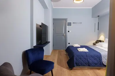a bedroom with a bed and a chair and a television at Sani Deluxe Suites Home- Monastiraki Square - Brand New Home in Athens