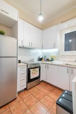 a kitchen with white cabinets and a white refrigerator at Athenslander Acropolis view in Athens