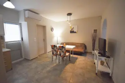 a living room with a table and chairs and a television at K&C Rooms- Apartments in Markopoulo